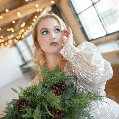 bride with evergreen bouquet under lights