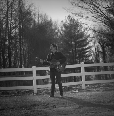 Folk musician Ketch Secor poses with guitar on a horse ranch for portraits on a Hasselblad film camera.