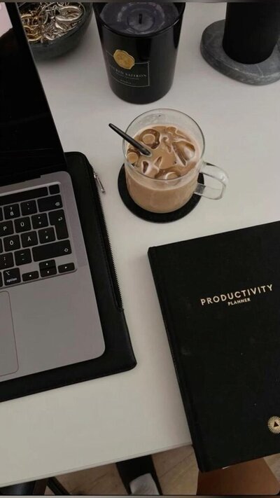 Laptop, coffee and notebook that shows Productivity on the cover