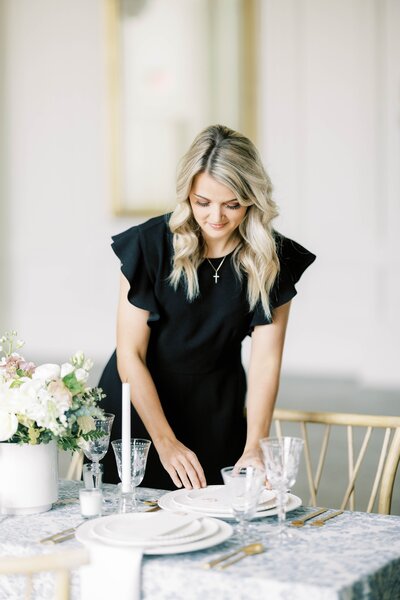 wedding planner decorates table with plates and silverware