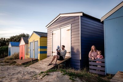 Family of four playing amongst the iconic Melbourne beach boxes