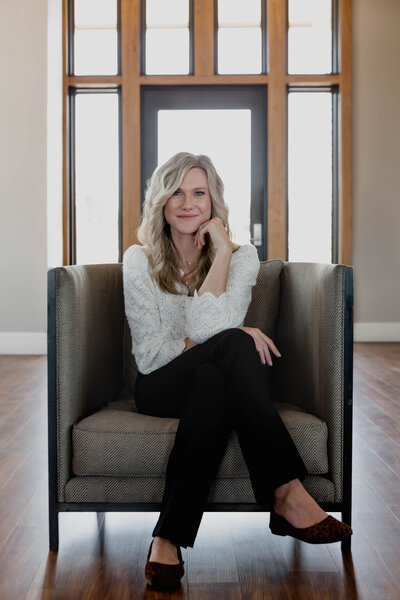 Kristin Tibbs smiling in a neutral-toned interior, ready to guide homeowners through luxury real estate sales in Colorado.