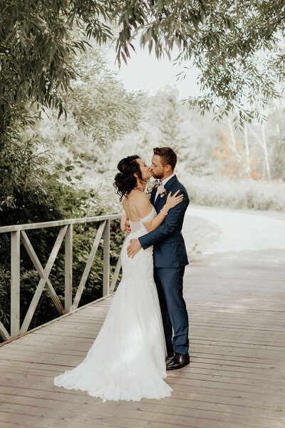 Newlyweds kissing on bridge