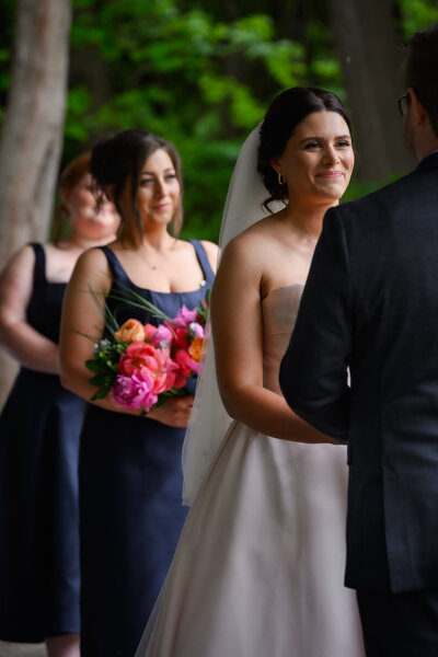 bride in pink with bridesmaids in navy blue dresses