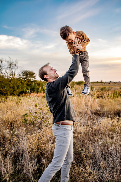 a dad lifts his son up at the park in the colony, texas