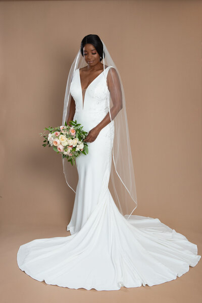 Bride wearing a floor length ribbon edged veil and holding a bouquet