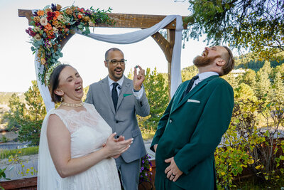 Officiant holding a DnD dice while the couple laughs during their wedding ceremony at Christies of Genesee in Colorado.