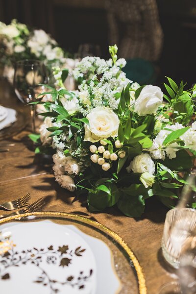 A timeless elegant table featuring the Pantone color of the year,  lined with cream pillar candles, amber and brown votive holders, and single double cream roses in  clear  bud vases spanning the length of the table