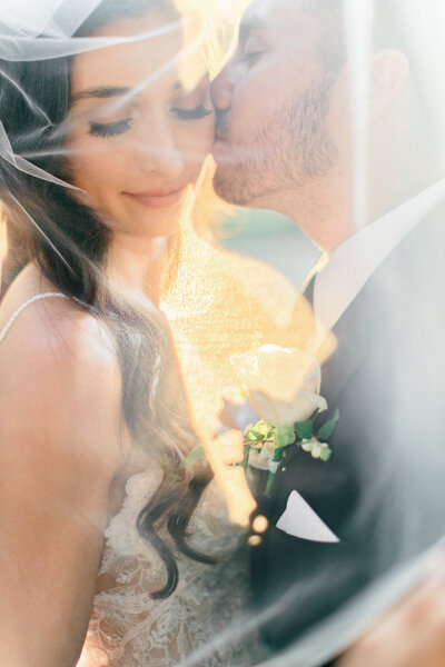 A romantic moment of a bride and groom sharing a quiet embrace under a delicate wedding veil, captured with timeless and elegant detail. This editorial image by Greenville wedding photographer Dani Lacey Photographs highlights the luxury and intimacy of a wedding day, perfect for couples seeking authentic, cinematic photography that tells their unique love story.