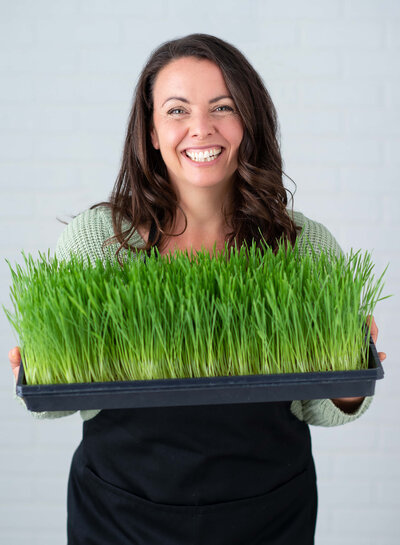 a female farmer holding a tray of grass