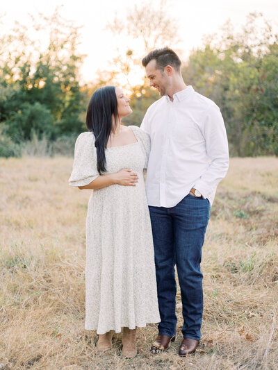 Mom-and-dad-cradling-baby-through-nursery-mirror-in-Austin