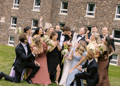 wedding party celebrating as bride and groom kiss