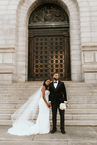 a newlywed couple holds hands outside of a monument in DC