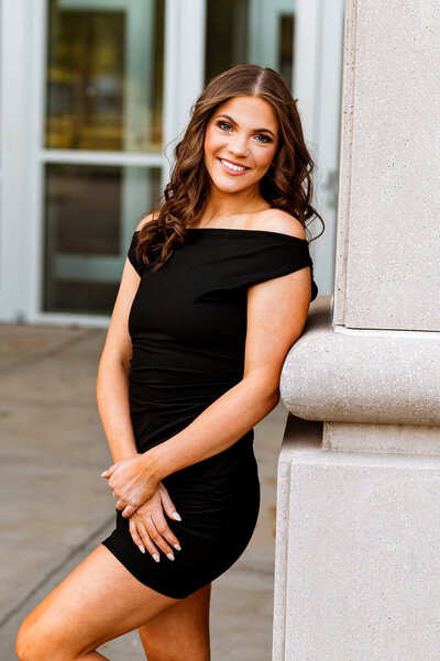 College senior girl smiling at camera wearing a black dress on the MTSU campus