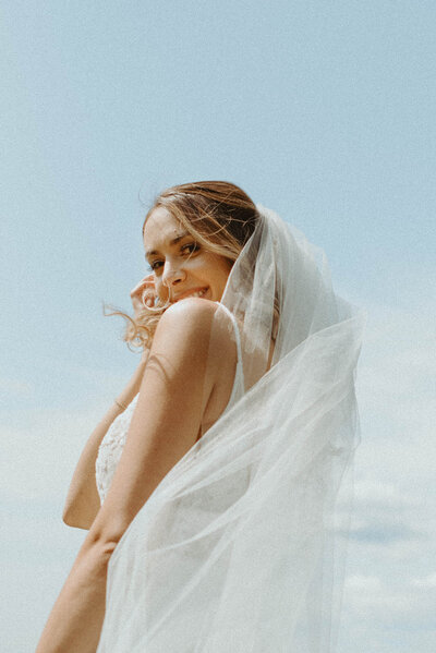 bride smiling with veil blowing in the wind