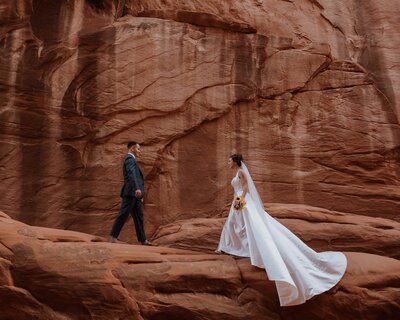 bride and groom holding hands and looking at each other while standing in the desert