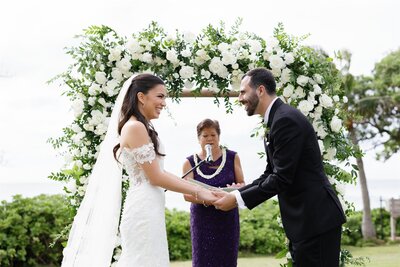 A couple holding hands and laughing during their wedding ceremony 
