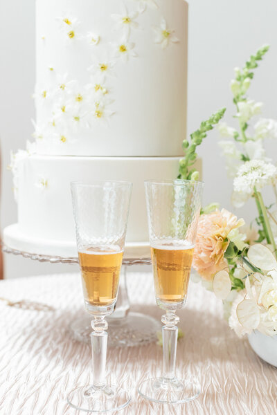 Two champagne glasses and a wedding cake on a table.
