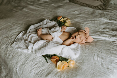 Newborn baby girl surrounded by flowers.