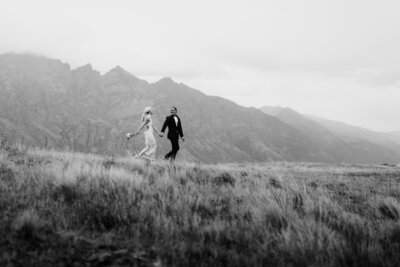 couple-holding-hands-in-front-of-queenstown-mountains