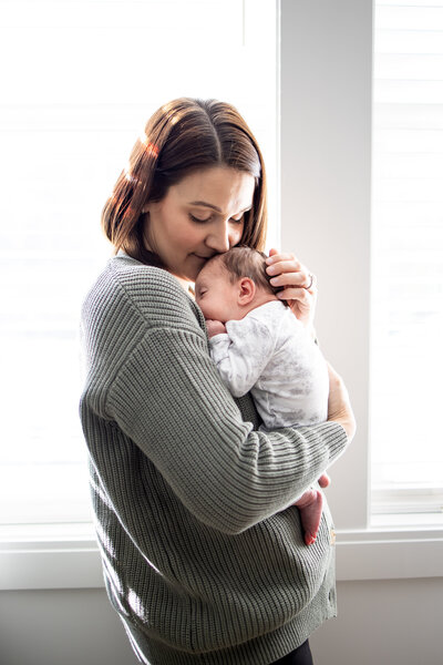 Mom holding baby girl in nursery in Boston, MA