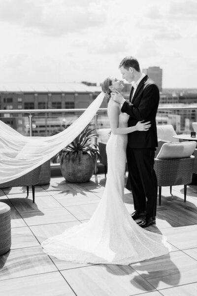 A bride and groom lean in for a kiss on the balcony at the Columbus AC Marriott downtown
