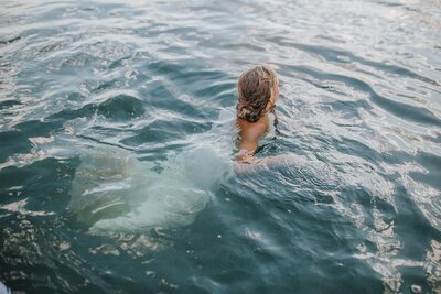 Sacramento Wedding Photographers capture bride swimming in water after wedding