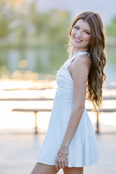 senior high school girl looking at the camera from her shoulder. She is wearing a white outfit. Photo taken in the nature of Boulder CO