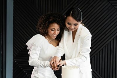 Two brides cutting cake