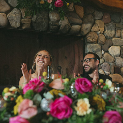 bride and groom clapping at wedding reception table