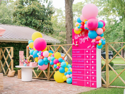 Pink scoreboard and colorful balloon arches for a wacky olympics event
