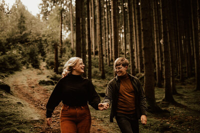 couple runs together in forest during pre shoot in sweden