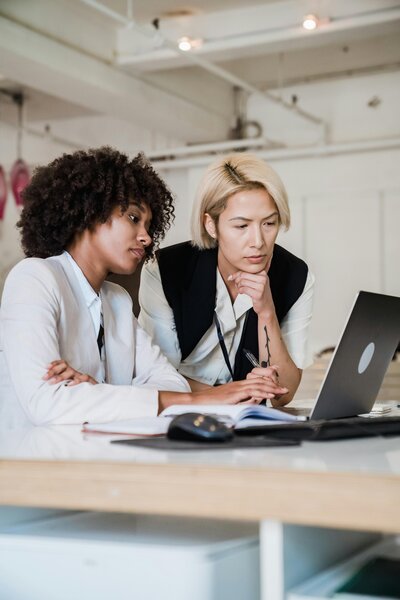 Two women looking at a Macbook screen