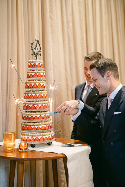 Un couple de mariés coupe leur gâteau de mariage qui se trouve à être un shortcake aux fraises de 8 étages.