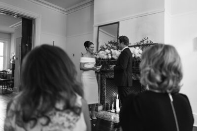 Bride and Groom in a white dress and blue shirt with khaki pants holding hands outside.