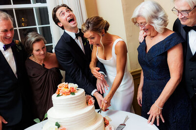 A couple laughing as they cut their wedding cake