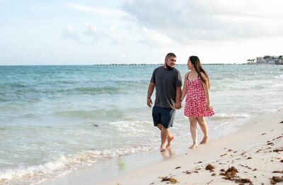 Photo of couple walking on the beach and looking at each other, vacation by destination wedding travel specialist CC Vacations