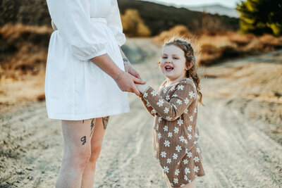 Small child holding hands with her mother in a desert scene near Lake Elsinore, CA.