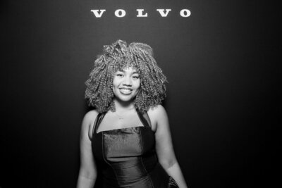 Guest posing in front of a black backdrop with Volvo branding, captured in black and white using Philly Snap Booth’s professional glam photo booth.