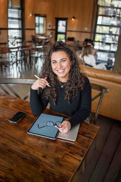 Tacoma business branding specialist woman sitting with iPad smiling sitting in cafe during branding photo shoot with photographer Lana Stewart Studios