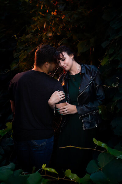Couple holding arms surrounded by fall vines.