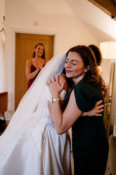 Weeding planner and bride hugging in a sweet embrace. 