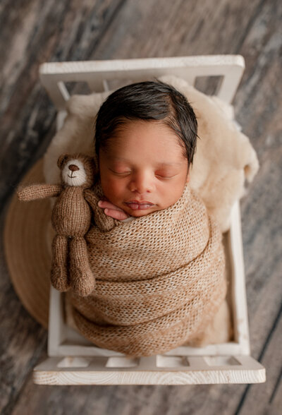 Mom and dad hold baby boy close to their chest in a newborn studio