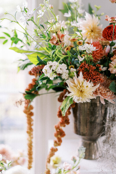 Close-up of a vibrant floral arrangement with dahlias and greenery in soft golden light at Oakville Golf Club