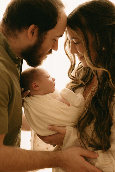Parents holding their newborn baby during in-studio family photo session