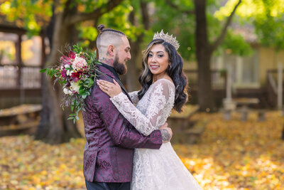 Wedding couples photoshoot  with man in purple suit coat and woman in wedding dress while wearing crown on her head