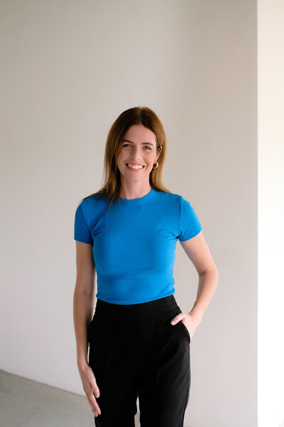 A woman strikes a pose in front of a large window, with gentle natural light creating soft shadows around her.