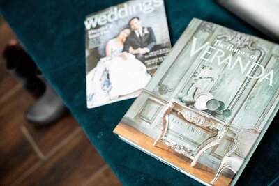 Wedding magazines and interior design books rest on a teal velvet bench.