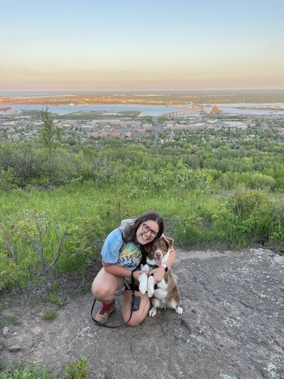 A person leaning down and hugging a dog on a hiking trail 