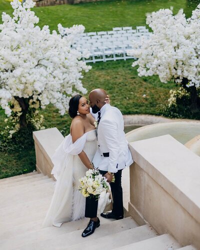 Couple walking down the Swan House lawn they are holding hands and the bride has her bouquet waving in the air smiling at each other